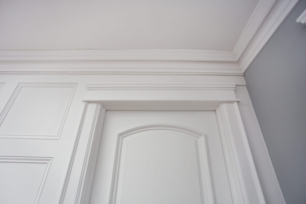 Achitrave above a moulded panel door beside feature wall