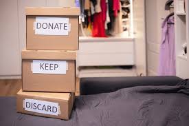 image of 3 boxes on bed , labelled donate, keep, discard respectively.